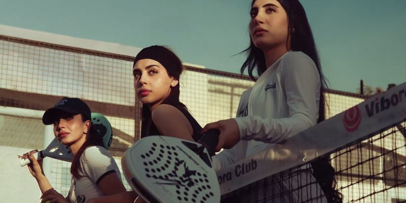 Three women with padel rackets at the net