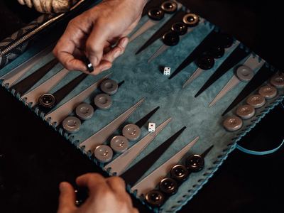 Two players' hands over a backgammon board