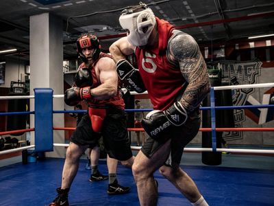 Two men sparring in a boxing ring with headgear