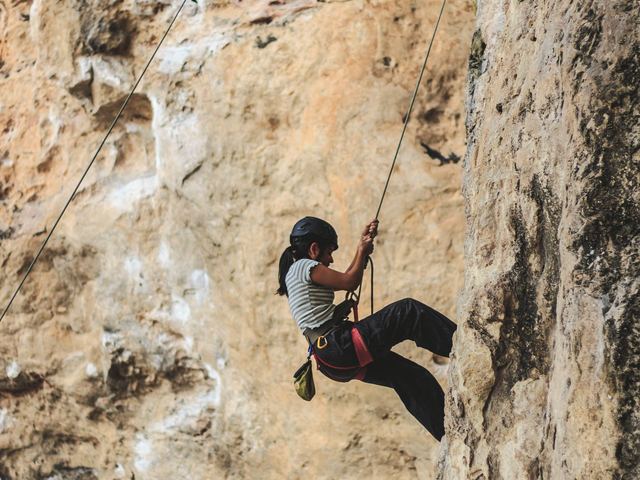 A woman climbing a rock face on a rope